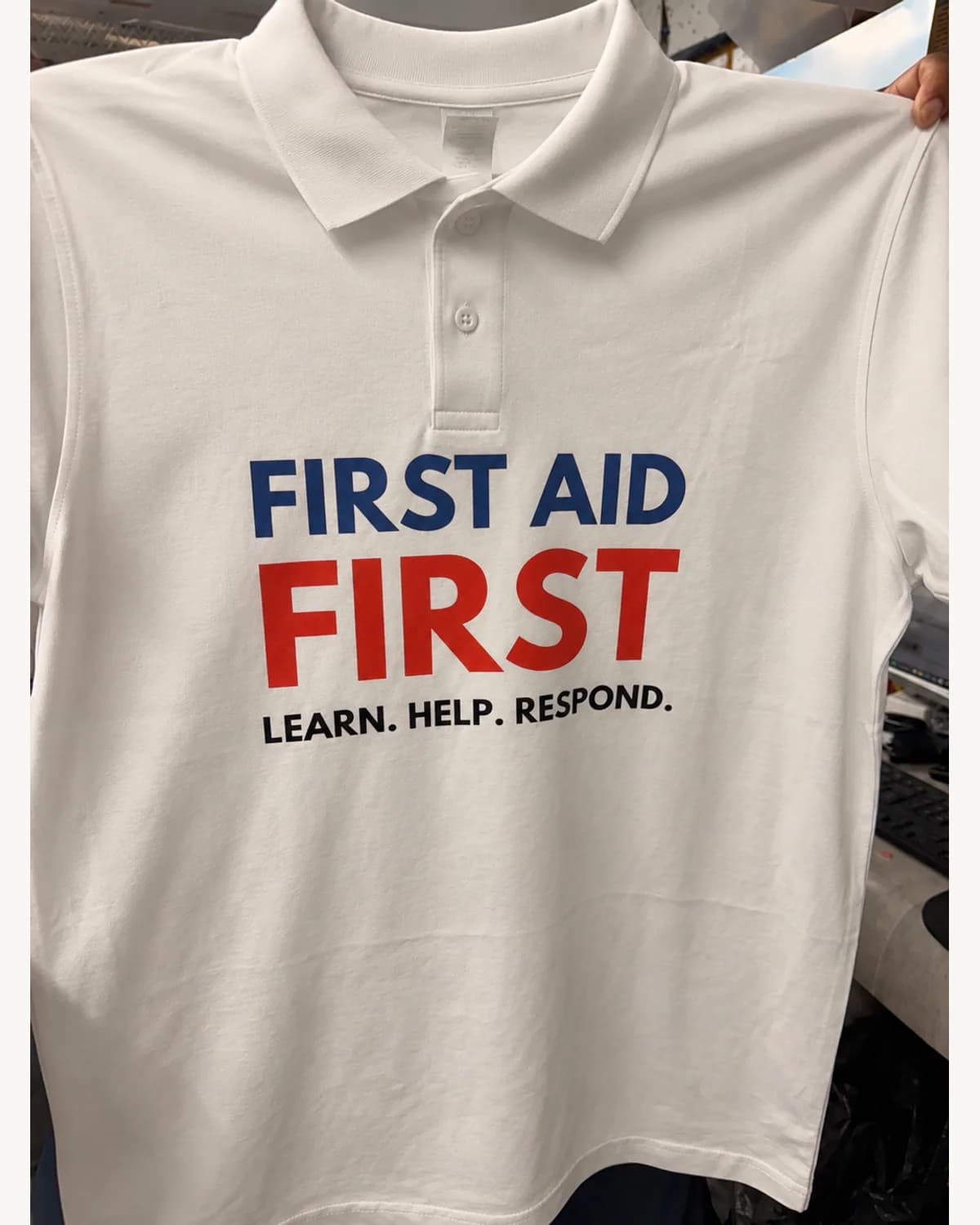 White polo shirt with a red blue and black training message