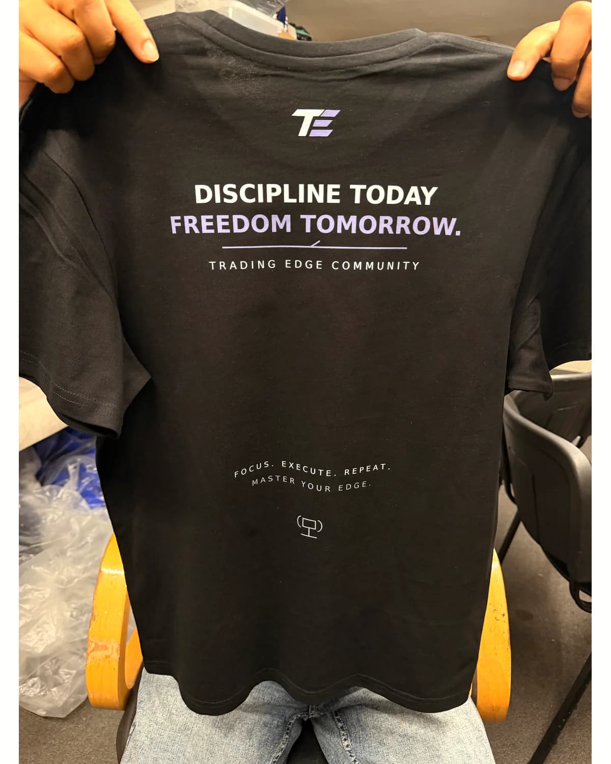 Black branded T shirt showing a larger main print and smaller secondary detail