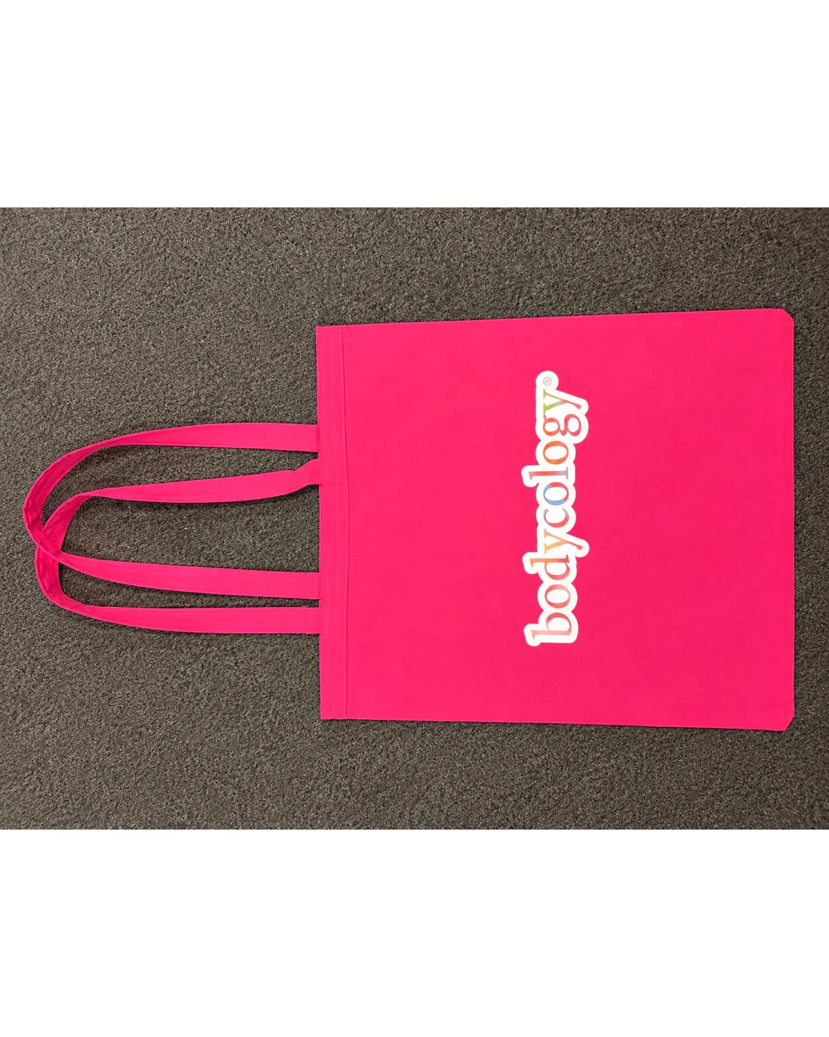 Bright pink tote bag with a white multicolour brand print