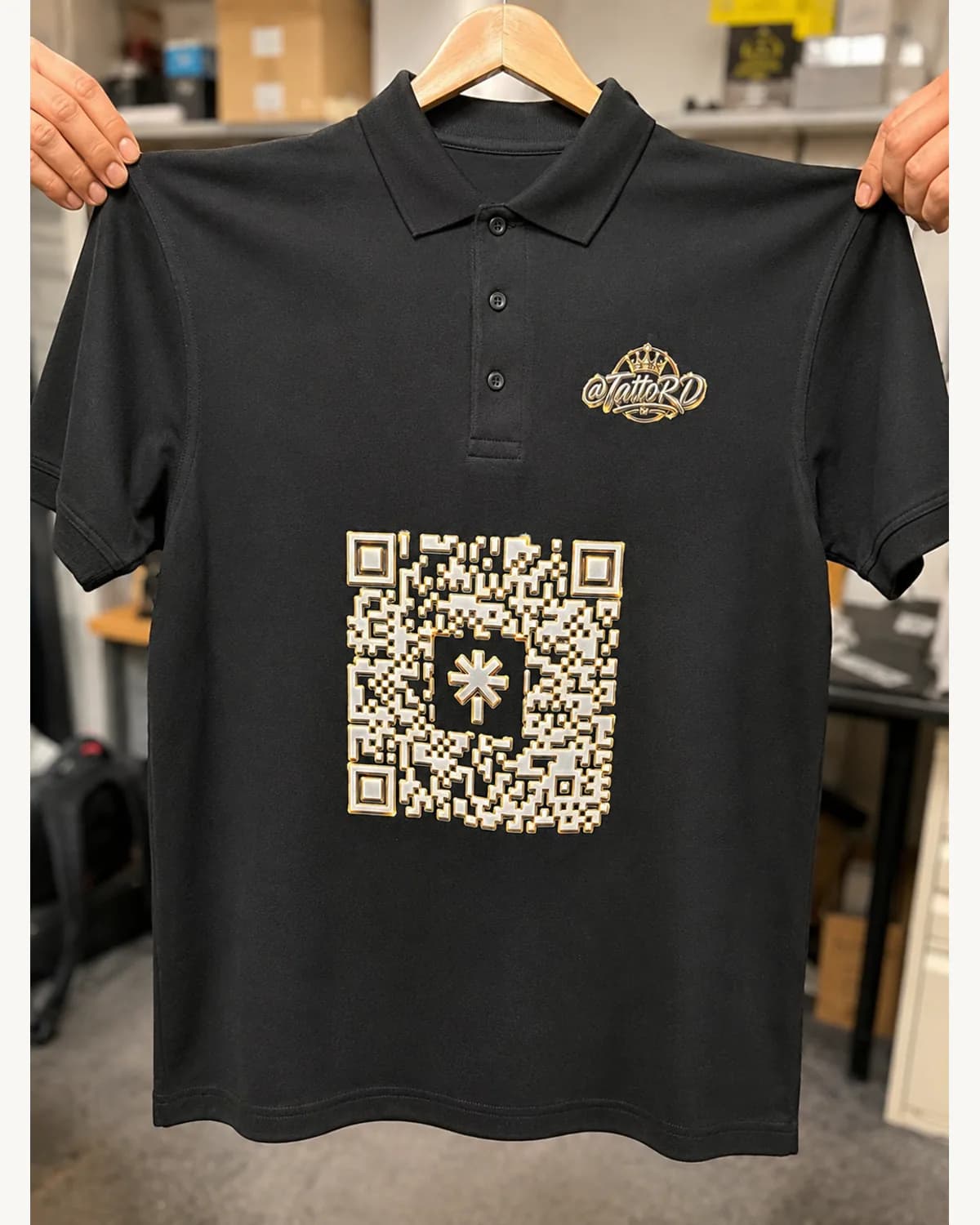 Black promotional polo with gold branding and a large QR code print