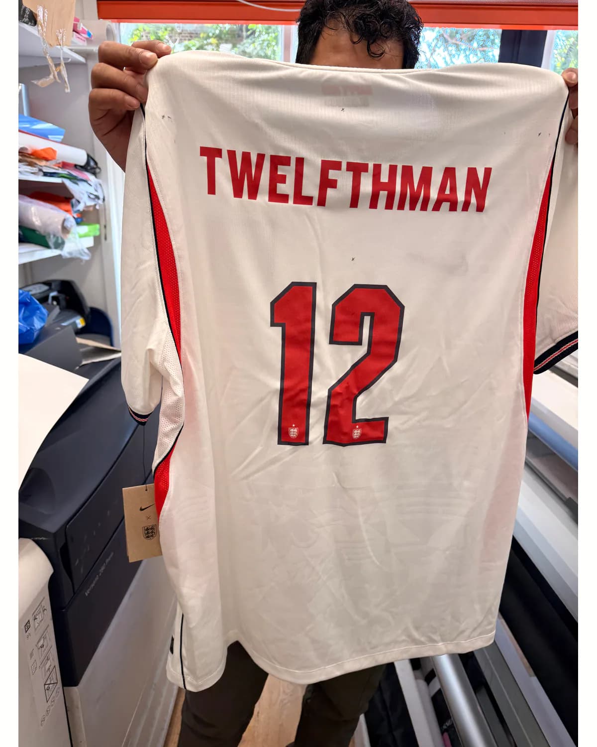 White sports jersey with a red team name and number 12